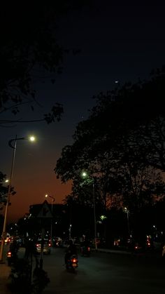 the night sky is lit up with street lights and cars parked on the side of the road