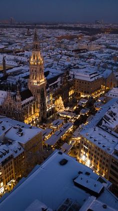 an aerial view of a city at night with snow on the ground and buildings lit up