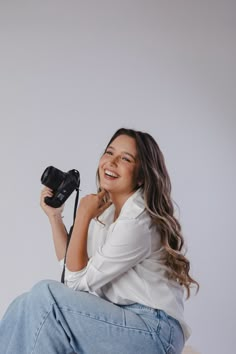 a woman sitting on top of a chair holding a camera