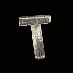 the letter t is made out of metal and has been scratched off with white paint