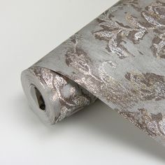 a close up of a silver tie on a white tablecloth with gold and silver flowers