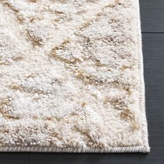 an area rug with white and gold designs on it