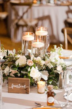 the table is set with white flowers and candles for an elegant centerpieces display