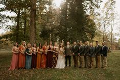 a group of people standing next to each other in front of some trees and grass