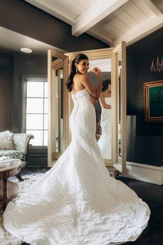 a woman in a white wedding dress is looking into a mirror and smiling at her reflection