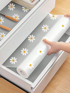 the drawer is open and has white flowers on it, while someone's hand reaches out