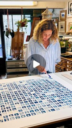 a woman standing in front of a table with blue and white tiles on the top