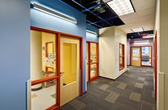 an empty office hallway with blue walls and yellow doors