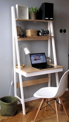 a laptop computer sitting on top of a wooden desk next to a white chair and shelf