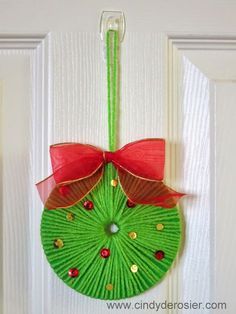 an ornament hanging on the front door with a red bow and green umbrella