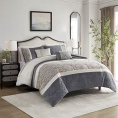 a bedroom with a large bed covered in gray and white comforters