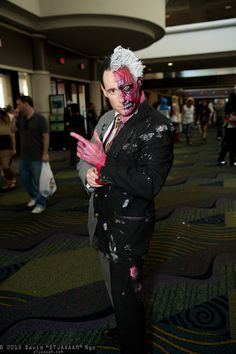 a man dressed up in a suit and painted face with pink paint on his hands