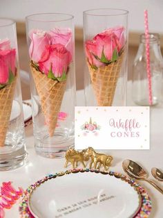 pink roses in an ice cream cone on a table with place cards and utensils