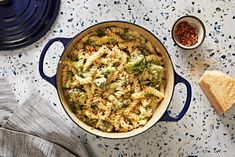 a casserole dish with broccoli, cheese and bread next to it