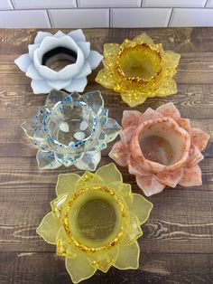 four glass flowers sitting on top of a wooden table