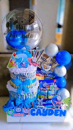 a blue and white birthday cake surrounded by balloons