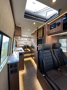 an interior view of a motor home with kitchen and living room area in the background