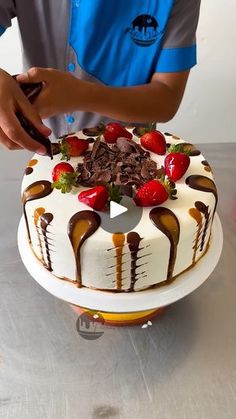 a man is cutting into a cake with chocolate and strawberries on the top,