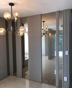 an empty room with mirrors and lights on the wall, in front of a door