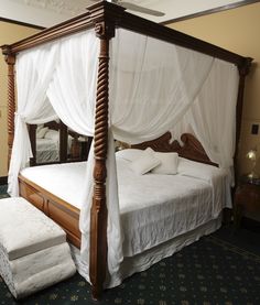 a four poster bed with white drapes on it's headboard and foot board