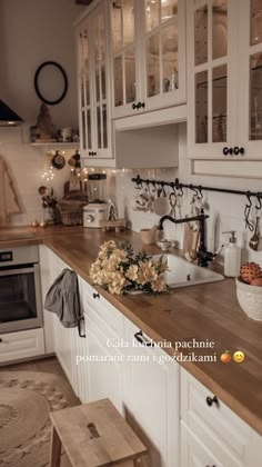 a kitchen with white cabinets and wooden counter tops, along with flowers on the island