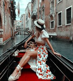 a woman sitting on the back of a boat while wearing a hat and dress in venice, italy