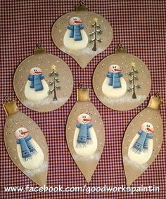 four christmas ornaments with snowmen on them sitting on a checkered cloth tablecloth