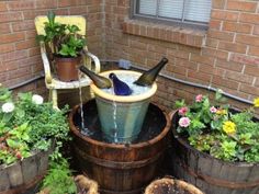 two bottles are sitting in a bucket filled with water next to some potted plants