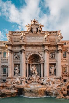 an ornate building with fountains and statues in front