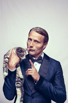 a man in a tuxedo holding a cat