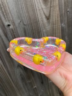 a hand holding a plastic toy with rubber ducks on it