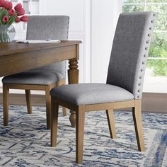 a dining room table with two chairs and a rug on the floor in front of it