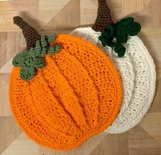 three crocheted pumpkins sitting on top of a wooden floor