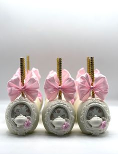 four miniature teapots with pink bows on them are sitting next to each other