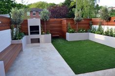 a small backyard with grass and wooden fenced in areas for plants, shrubs and trees