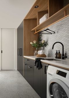 a washer and dryer in a small room next to a wall with shelving