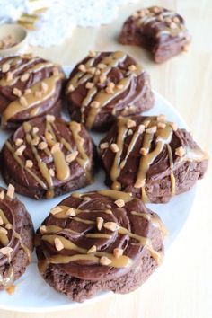 chocolate cookies with peanut butter drizzled on them sitting on a white plate