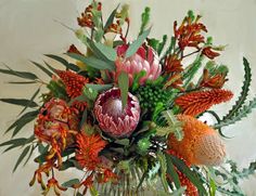 a vase filled with lots of different types of flowers and greenery on top of a table