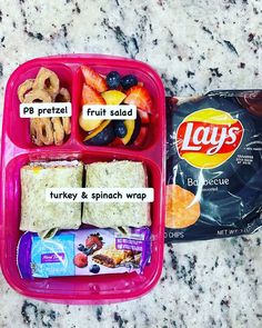 the lunch box is packed with fruit, crackers, and other foodstuffs