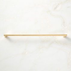 a white marble counter top with a gold colored metal bar on the left hand side