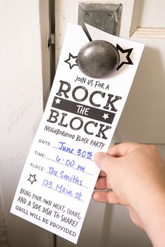 a person holding up a rock the block ticket to someones birthday party in front of a door