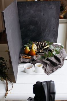 an open black box sitting on top of a table next to two cups and fruit