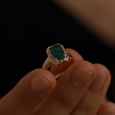 a person holding an emerald ring in their hand