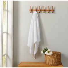 a white towel hanging on a wall next to a basket with flowers and a potted plant