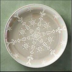 a white plate with flowers on it sitting on top of a green tableclothed surface