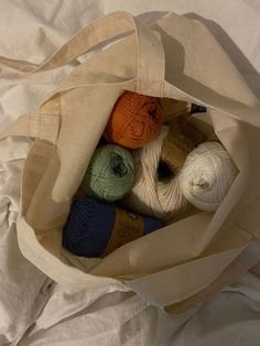 several balls of yarn are in a canvas bag