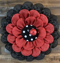 a red and black mesh wreath with a ladybug on it's center