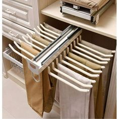 an open drawer with clothes hanging from it's sides and folded towels on the bottom