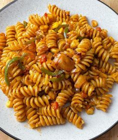 a white plate topped with pasta covered in sauce and green peppers on top of it