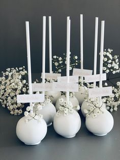 several white vases with flowers and candles in them